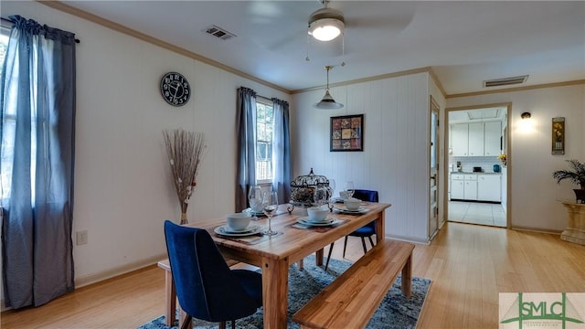 dining space with crown molding, ceiling fan, and light wood-type flooring