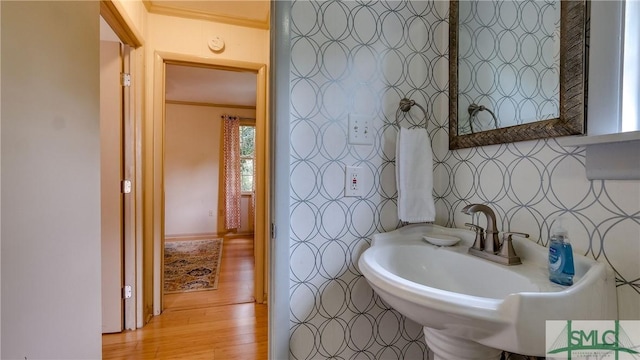 bathroom featuring hardwood / wood-style flooring, ornamental molding, and sink