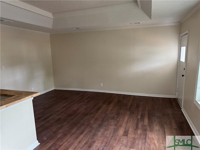 unfurnished living room with dark hardwood / wood-style flooring, a raised ceiling, and ornamental molding