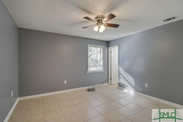 spare room featuring ceiling fan, light tile patterned flooring, and a textured ceiling