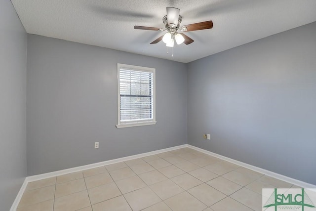 empty room featuring ceiling fan, light tile patterned flooring, and a textured ceiling