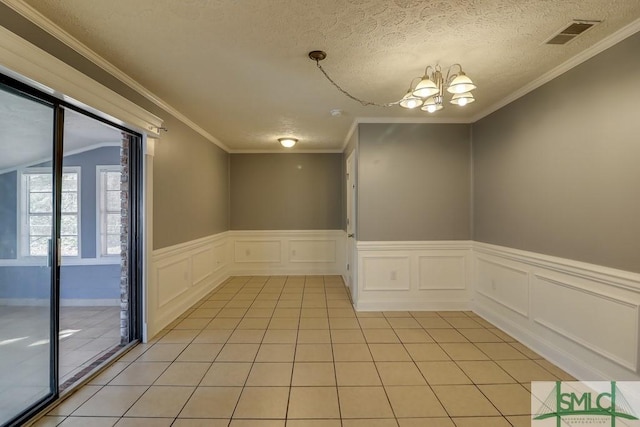 tiled spare room featuring a chandelier, a textured ceiling, and ornamental molding