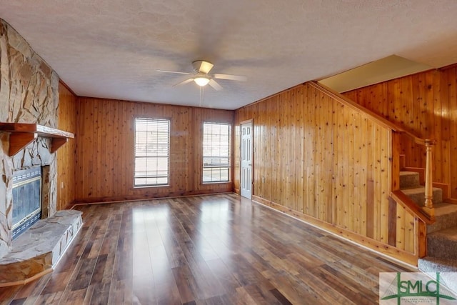 unfurnished living room featuring ceiling fan, a fireplace, wood-type flooring, and a textured ceiling