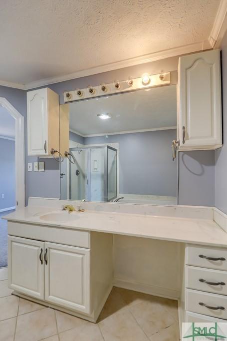 bathroom with vanity, tile patterned flooring, ornamental molding, a textured ceiling, and a shower with shower door