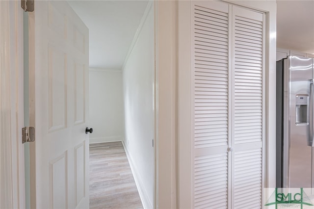 corridor with light hardwood / wood-style floors and ornamental molding