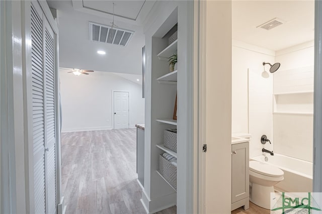 full bathroom with hardwood / wood-style floors, vanity, shower / washtub combination, built in shelves, and toilet