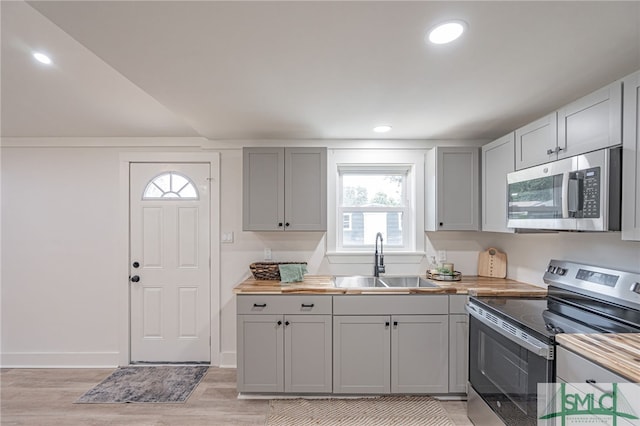 kitchen featuring wood counters, sink, gray cabinets, appliances with stainless steel finishes, and light hardwood / wood-style floors