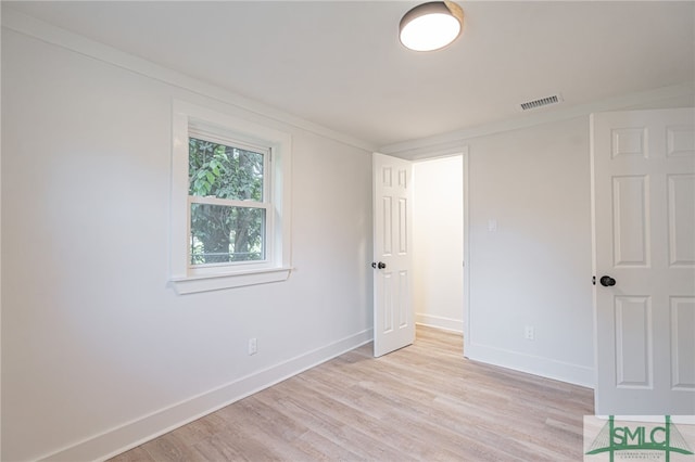 spare room with crown molding and light hardwood / wood-style flooring