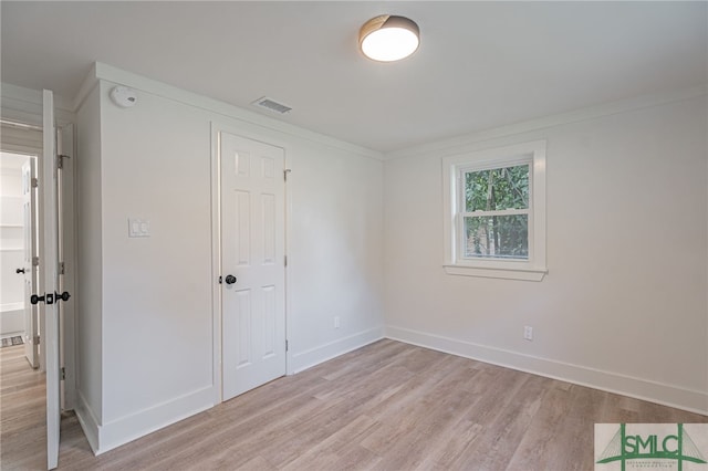 unfurnished room with light wood-type flooring and crown molding