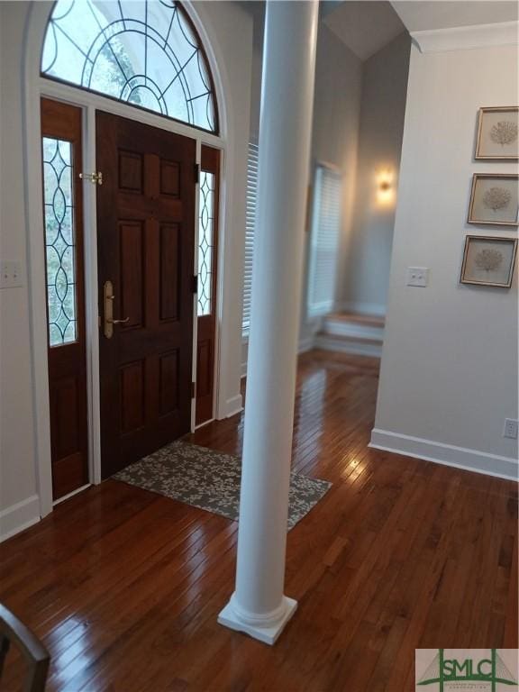 foyer with dark hardwood / wood-style floors, ornamental molding, and decorative columns