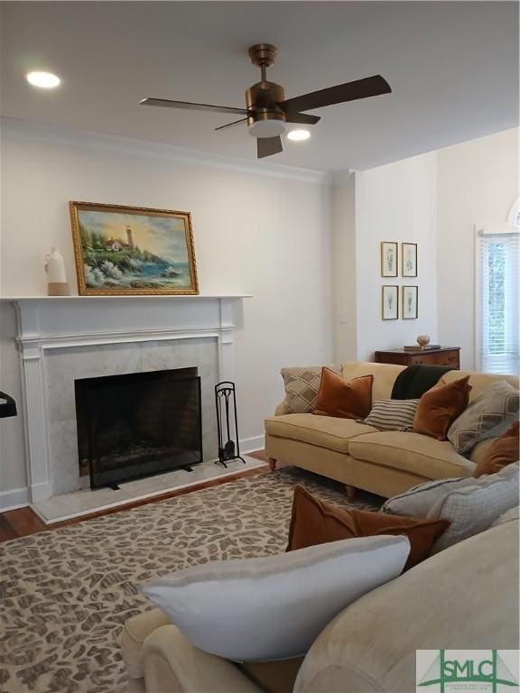 living room featuring crown molding, ceiling fan, a fireplace, and wood-type flooring