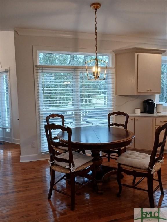 dining space featuring dark hardwood / wood-style flooring, an inviting chandelier, and crown molding