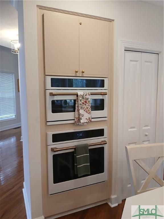 kitchen with multiple ovens and dark wood-type flooring