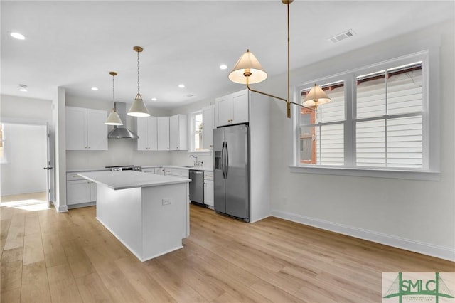 kitchen with decorative light fixtures, a center island, stainless steel appliances, and white cabinetry