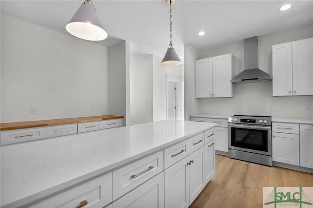 kitchen featuring light wood-type flooring, wall chimney exhaust hood, electric range, white cabinetry, and hanging light fixtures