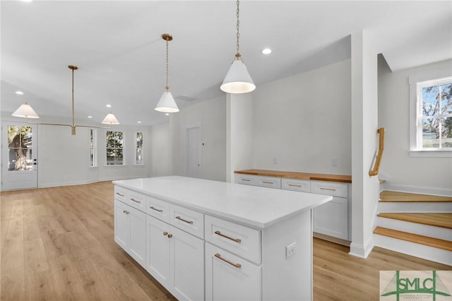 kitchen featuring a wealth of natural light, a center island, white cabinetry, and hanging light fixtures