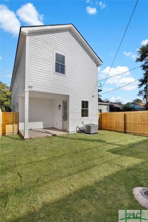 rear view of property featuring a lawn, cooling unit, and a patio