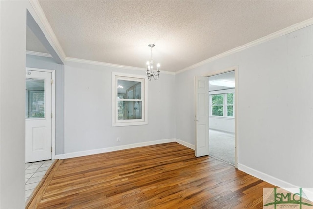 spare room with wood-type flooring, a textured ceiling, an inviting chandelier, and ornamental molding