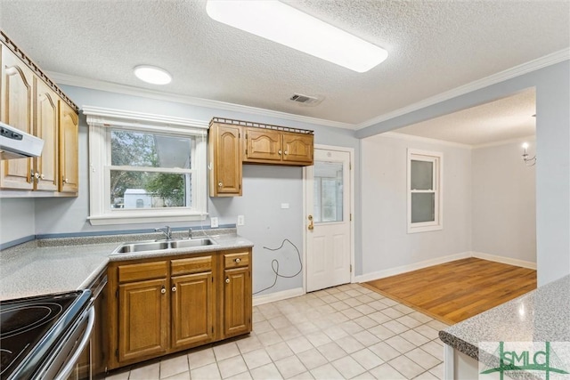 kitchen with sink, light tile patterned flooring, a textured ceiling, and ornamental molding