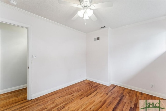 empty room featuring a textured ceiling, hardwood / wood-style flooring, ceiling fan, and ornamental molding