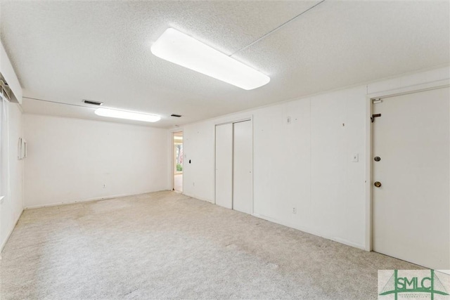 basement featuring light carpet and a textured ceiling