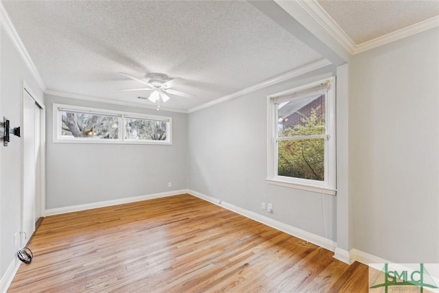 empty room with ceiling fan, light hardwood / wood-style floors, a textured ceiling, and ornamental molding