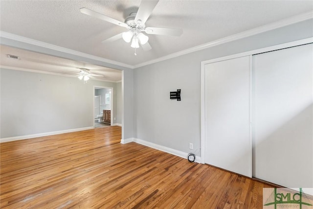 empty room with ceiling fan, light wood-type flooring, ornamental molding, and a textured ceiling