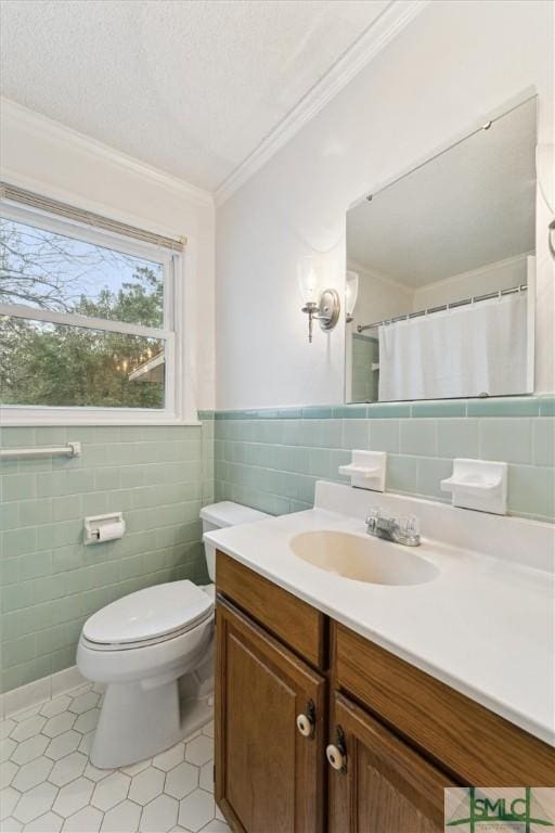 bathroom featuring vanity, toilet, ornamental molding, a textured ceiling, and tile walls