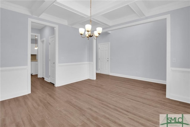 unfurnished dining area featuring beam ceiling, wood-type flooring, coffered ceiling, and an inviting chandelier