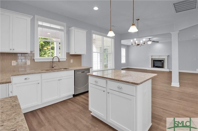 kitchen with backsplash, white cabinets, sink, hanging light fixtures, and stainless steel dishwasher