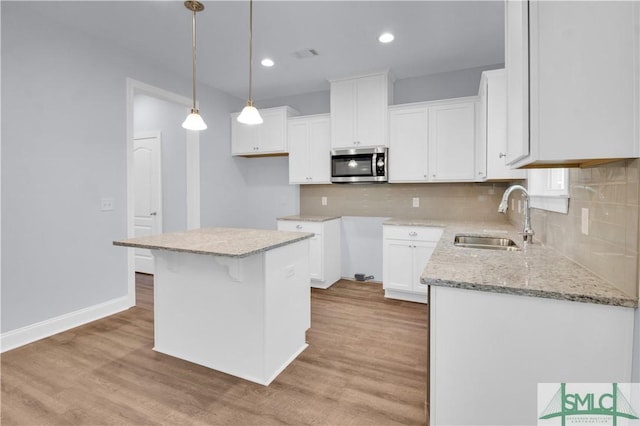 kitchen featuring a center island, sink, white cabinets, and decorative light fixtures