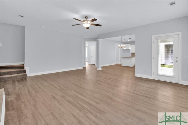 unfurnished living room with ceiling fan with notable chandelier and hardwood / wood-style flooring