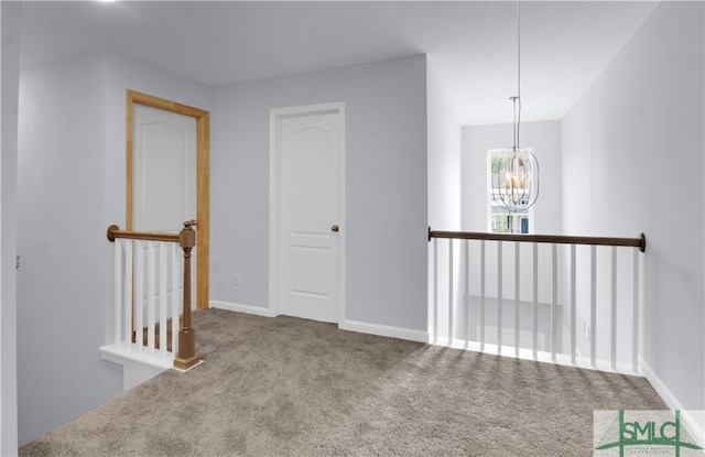 carpeted spare room with a chandelier