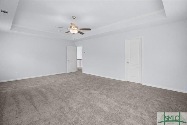 carpeted spare room with a tray ceiling and ceiling fan