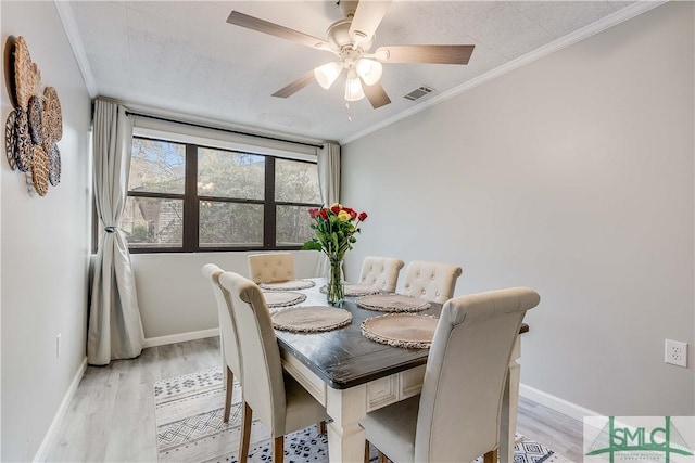 dining space with ceiling fan, light hardwood / wood-style floors, and crown molding