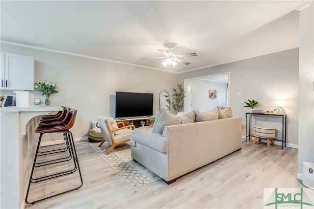 living room with ceiling fan, light wood-type flooring, and ornamental molding