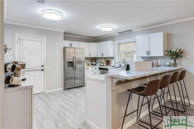 kitchen with a kitchen breakfast bar, white cabinetry, crown molding, and appliances with stainless steel finishes