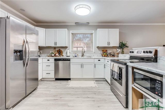 kitchen featuring light stone countertops, ornamental molding, stainless steel appliances, sink, and white cabinets