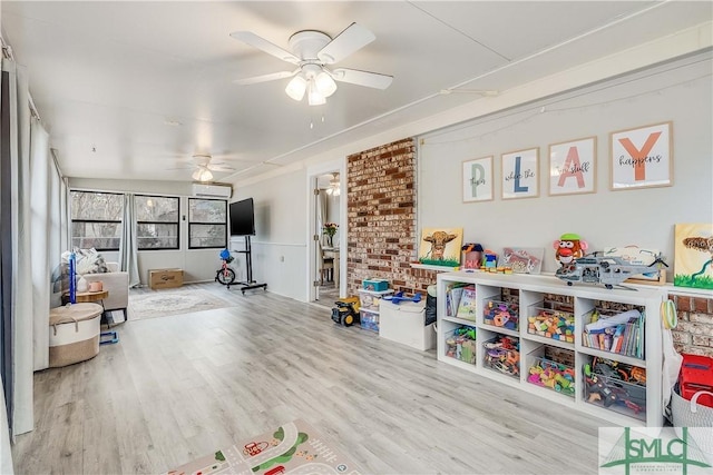 playroom with an AC wall unit, ceiling fan, and light hardwood / wood-style floors