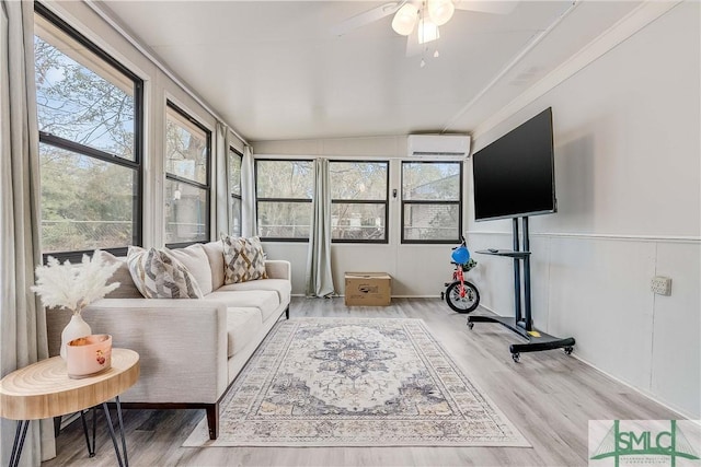 living room featuring a wall unit AC, ceiling fan, and wood-type flooring