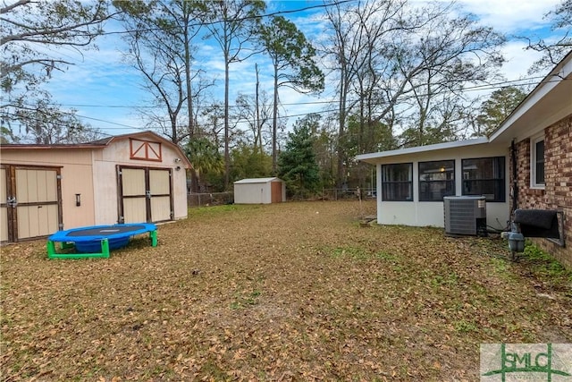 view of yard featuring a sunroom, a trampoline, a storage unit, and central air condition unit