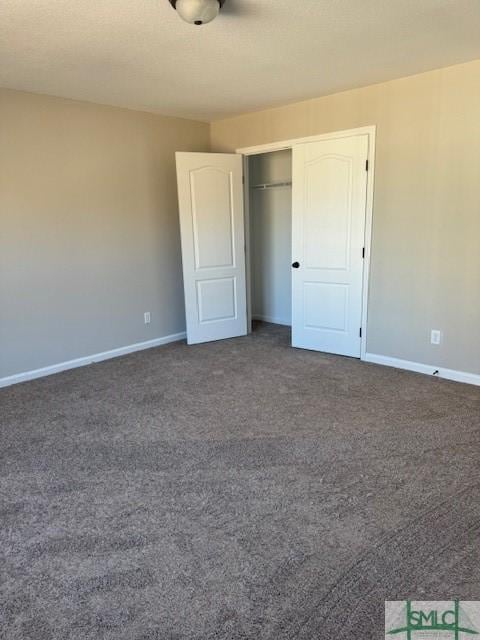 unfurnished bedroom featuring dark carpet and a closet