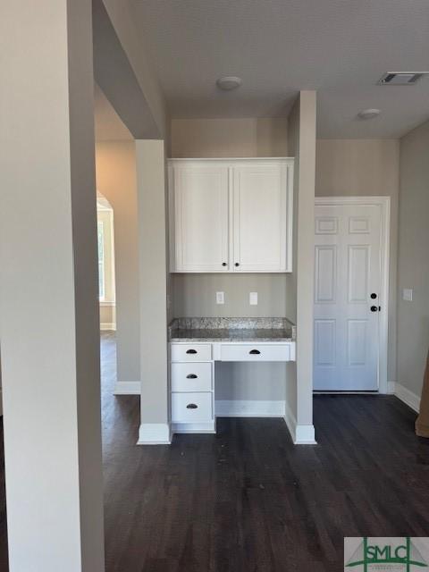 kitchen with dark hardwood / wood-style floors, built in desk, and white cabinetry