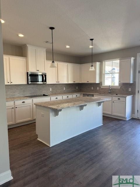 kitchen featuring white cabinets, pendant lighting, a kitchen island, and a breakfast bar area