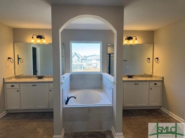 bathroom featuring tiled tub and vanity