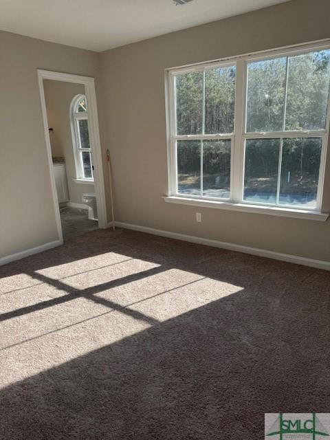 empty room with dark colored carpet and plenty of natural light