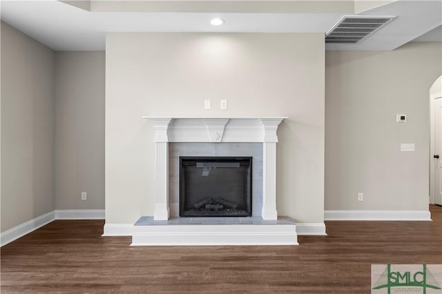 interior details featuring a glass covered fireplace, wood finished floors, visible vents, and baseboards