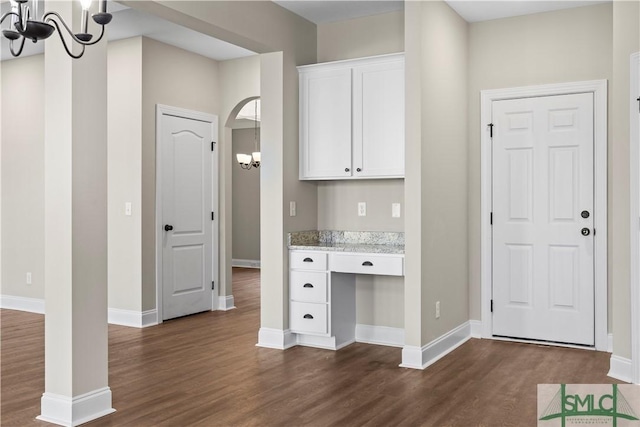 interior space with a chandelier, dark wood-style floors, white cabinets, and built in study area