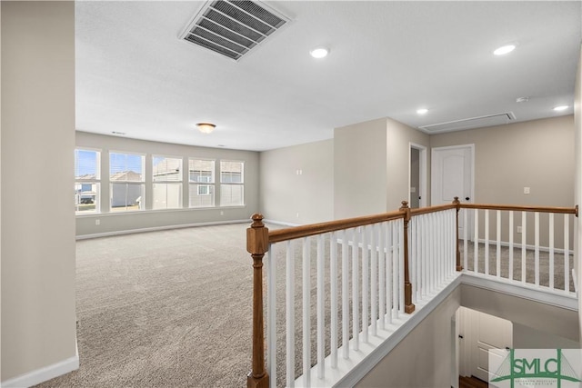 hall with baseboards, visible vents, attic access, recessed lighting, and carpet flooring