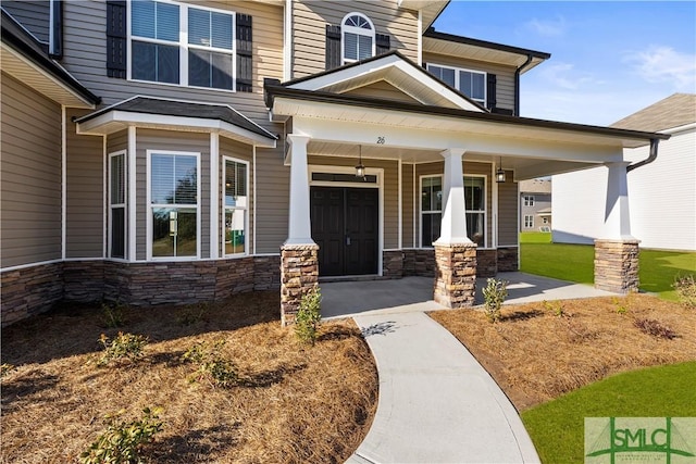 doorway to property with stone siding and a porch